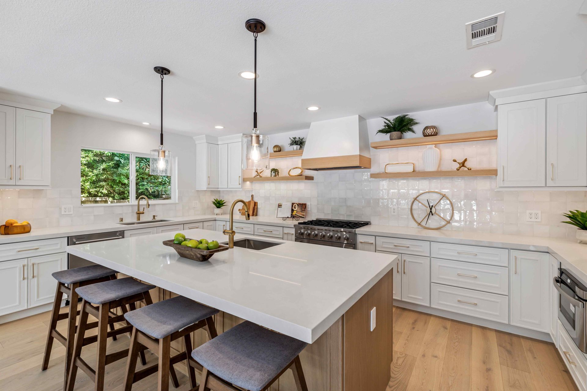 Bright modern white kitchen with island, pendant lights, stools, and wood floors