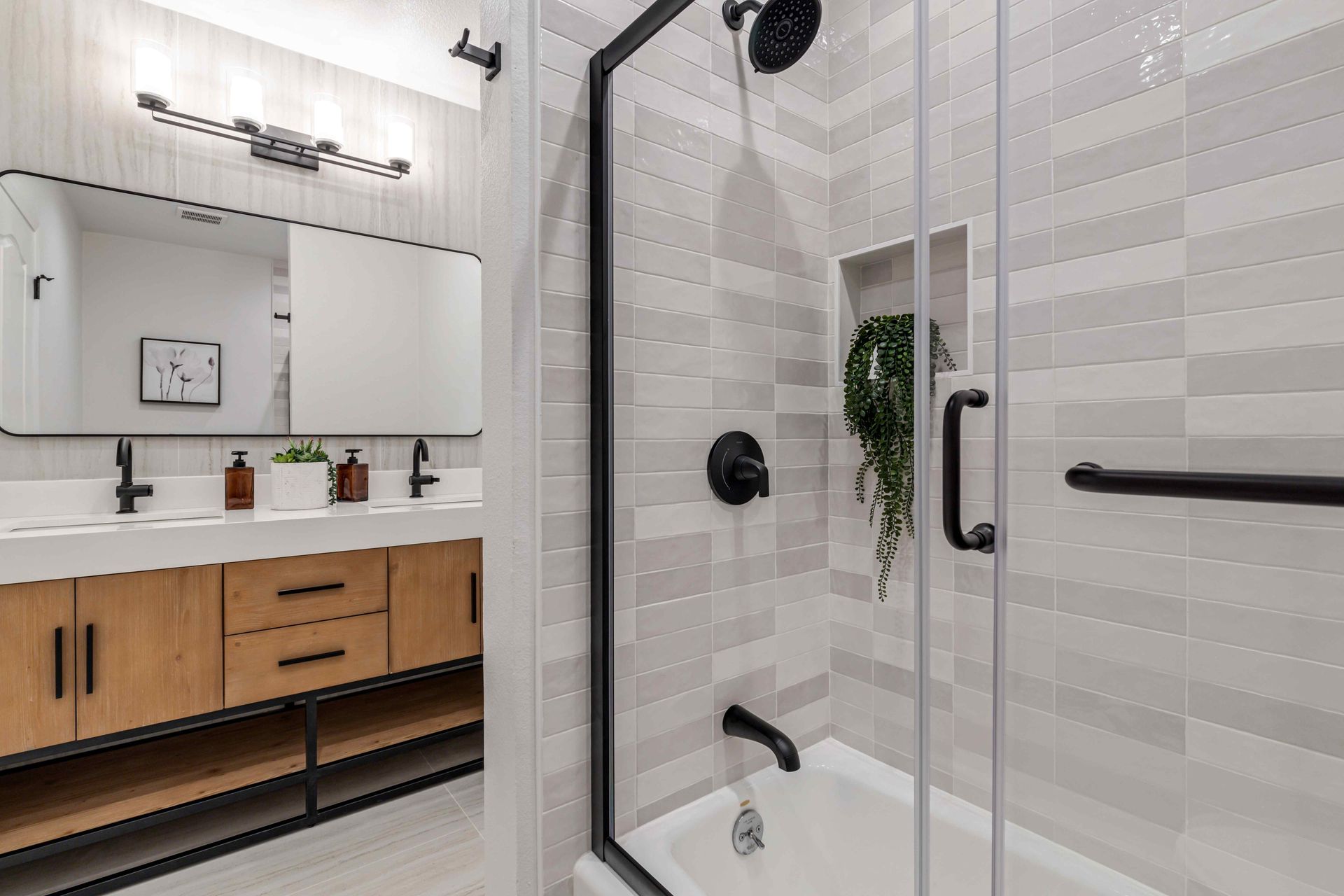 Modern bathroom with glass shower, wood vanity, and large mirror in bright neutral tones