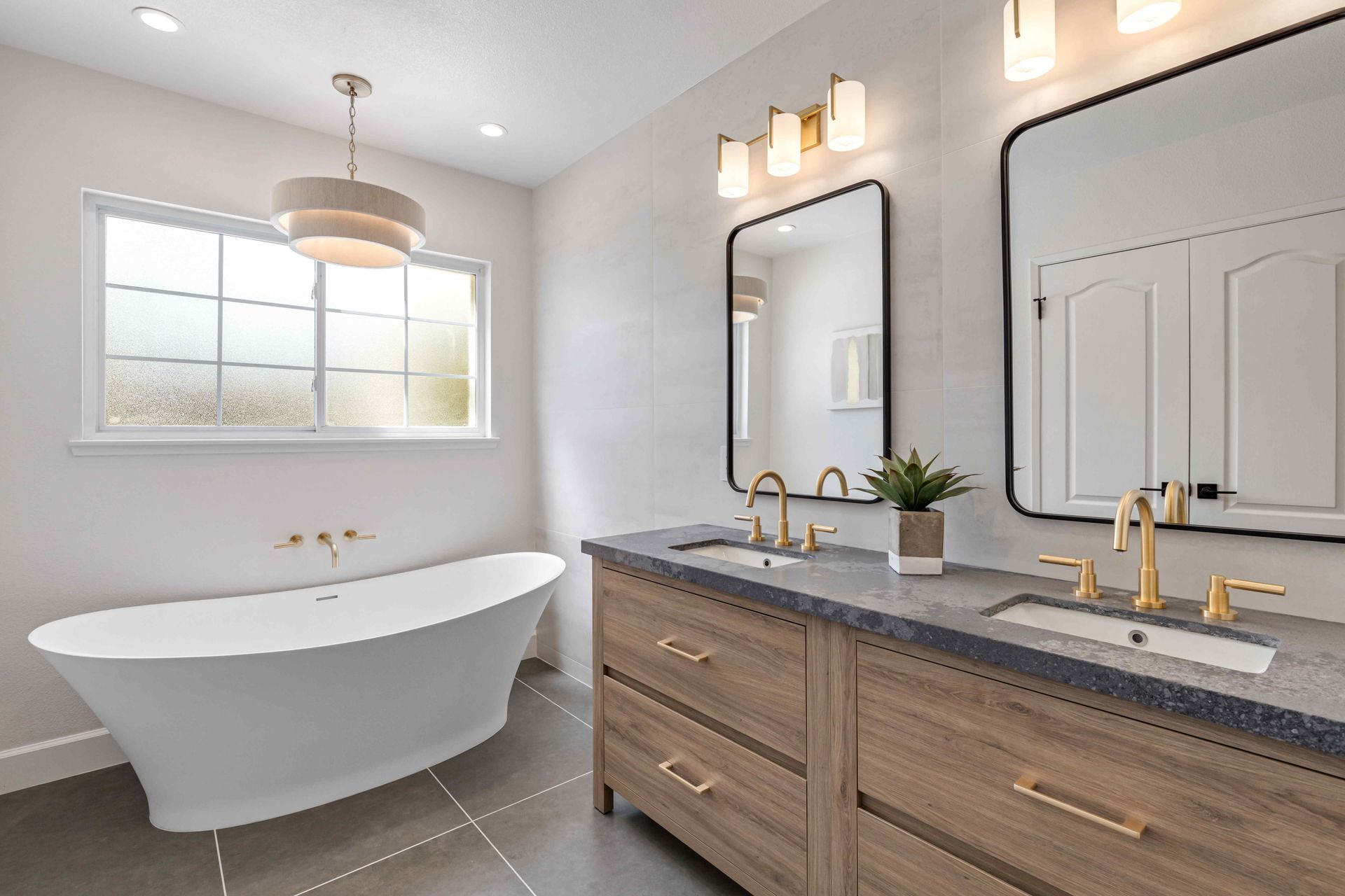 Bright modern bathroom with freestanding tub, double vanity, and large window