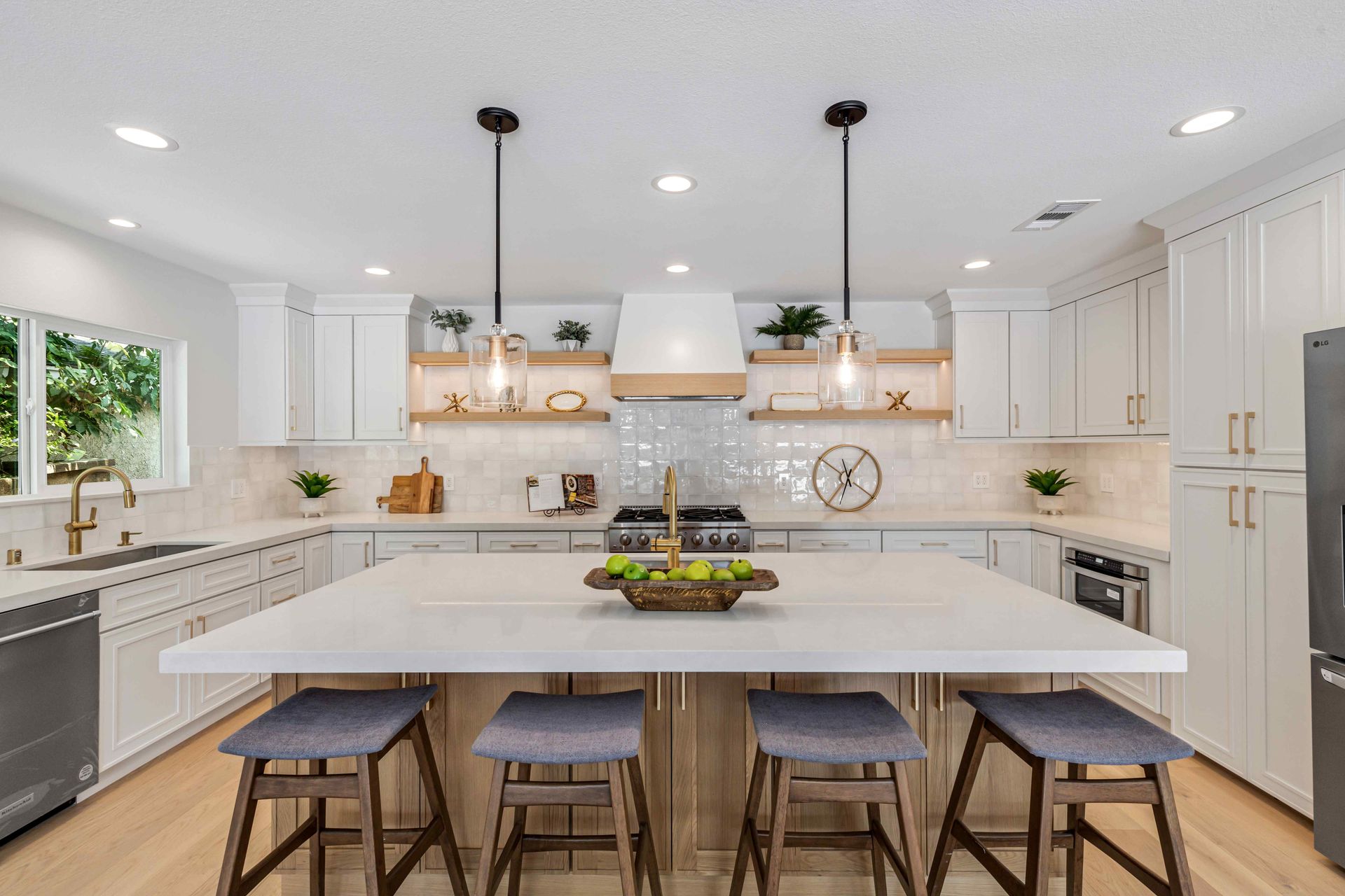 Bright modern white kitchen with island, pendant lights, and five stools
