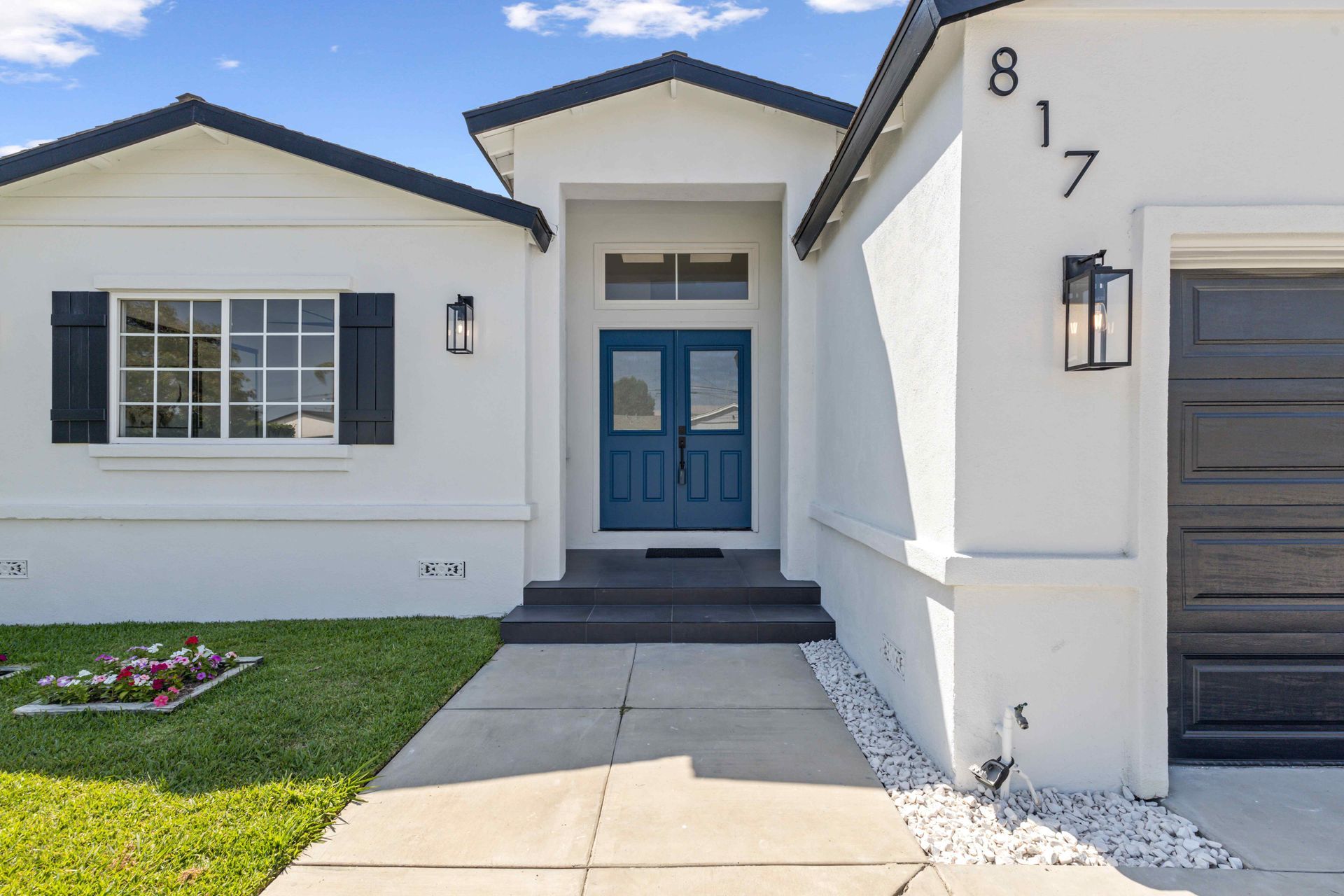 Front entrance of a white house with blue door, black shutters, walkway, and house number 817.