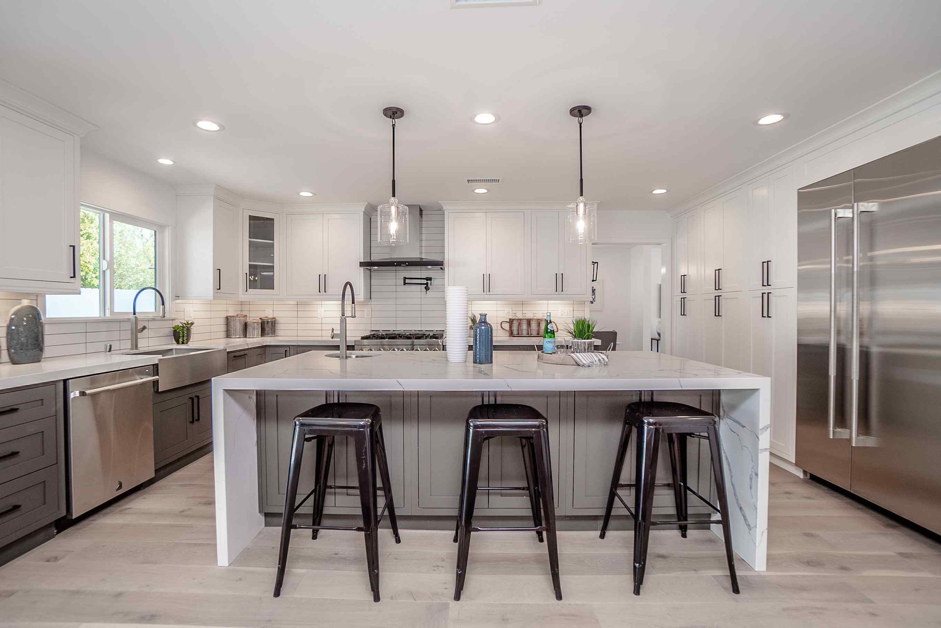 White kitchen with stainless steel appliances, light cabinets, and marble tile backsplash.