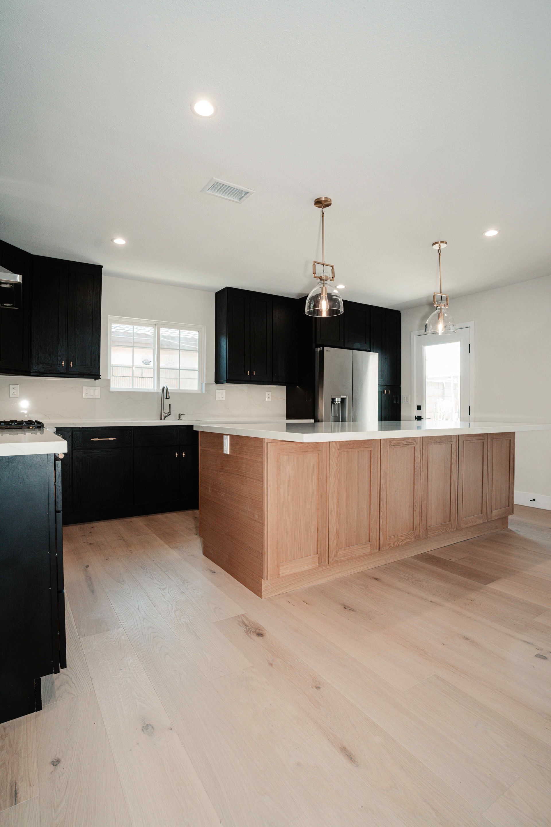 Modern kitchen with dark cabinets, white countertops, wood island, and light wood flooring