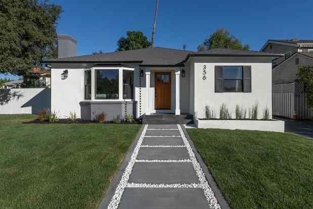 White house with gray trim, pathway, and green lawn.