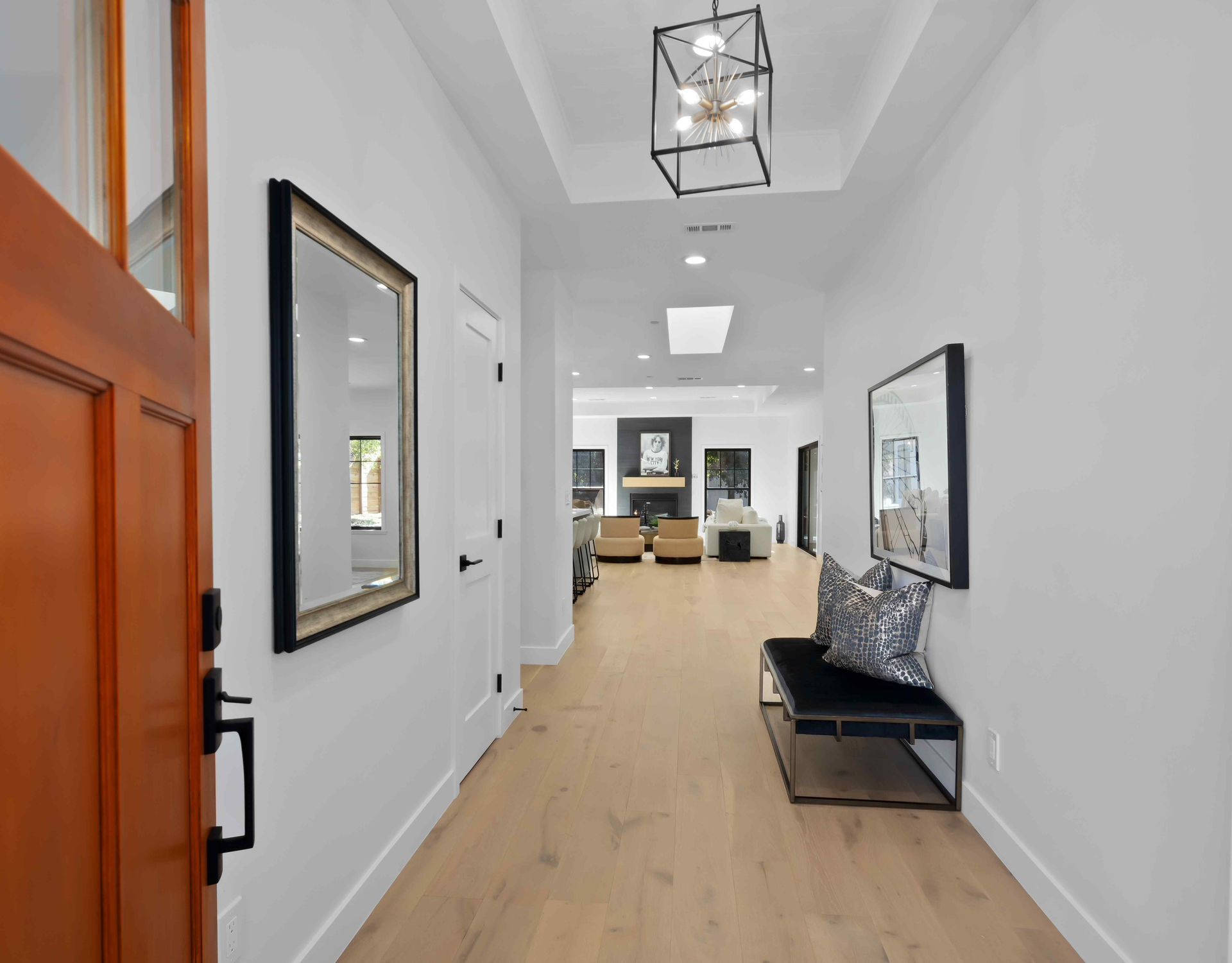 A bright entryway with wood floors, white walls, and a black bench.