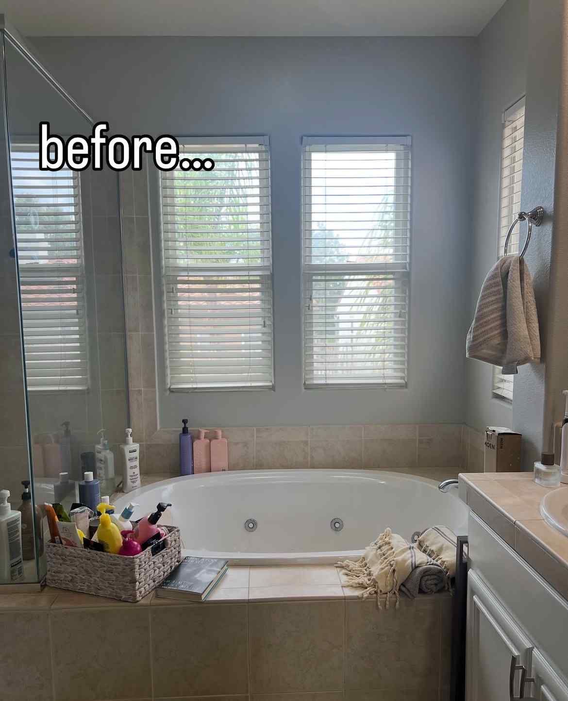 Bathroom before renovation: bathtub, windows with blinds, neutral walls.