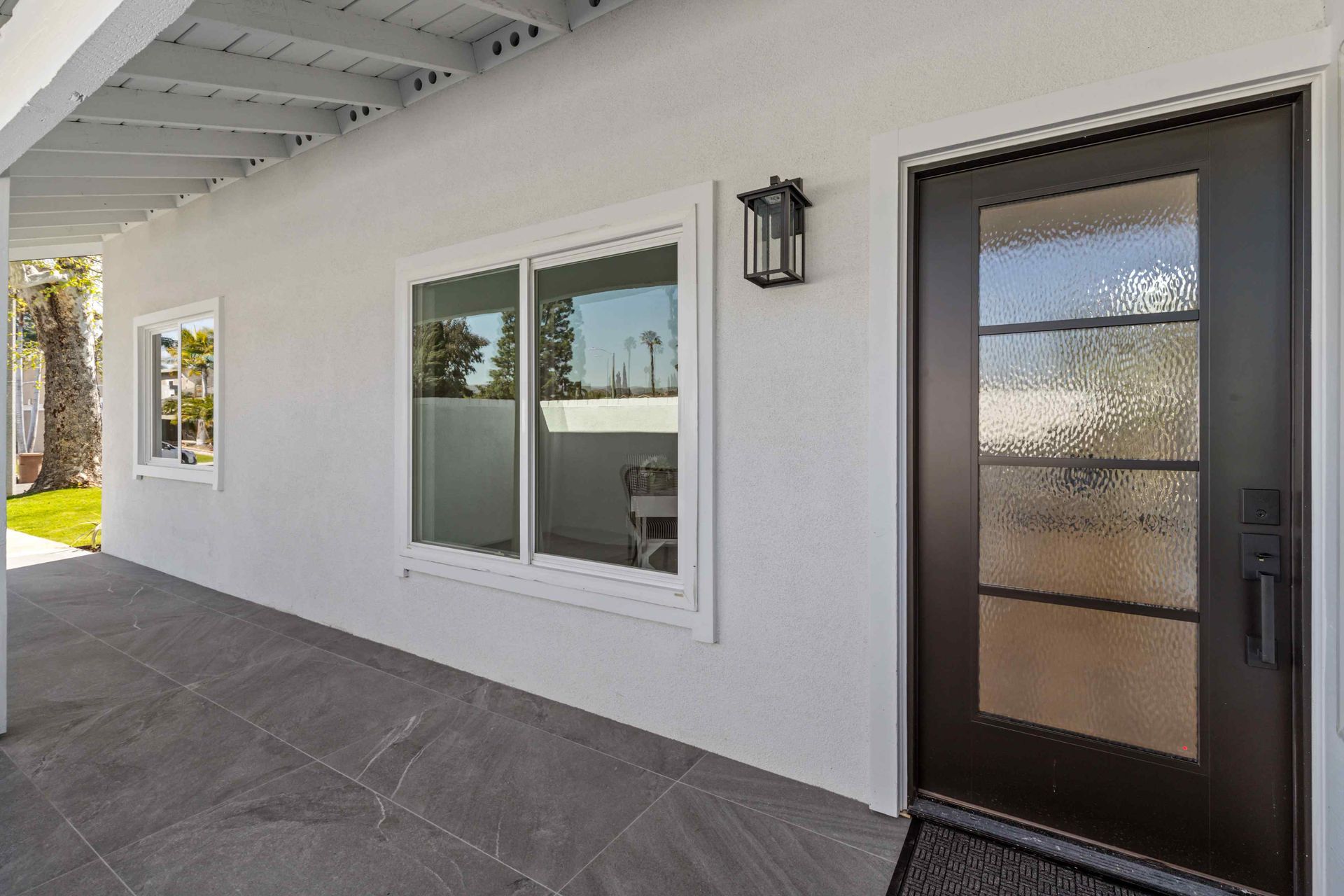 White exterior with dark door and windows, stone patio.