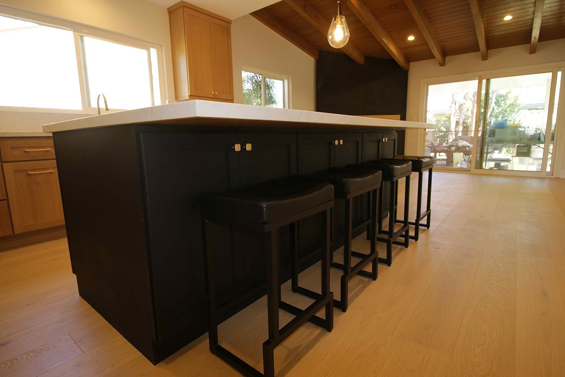 Modern kitchen with black island and stools in a bright open living space