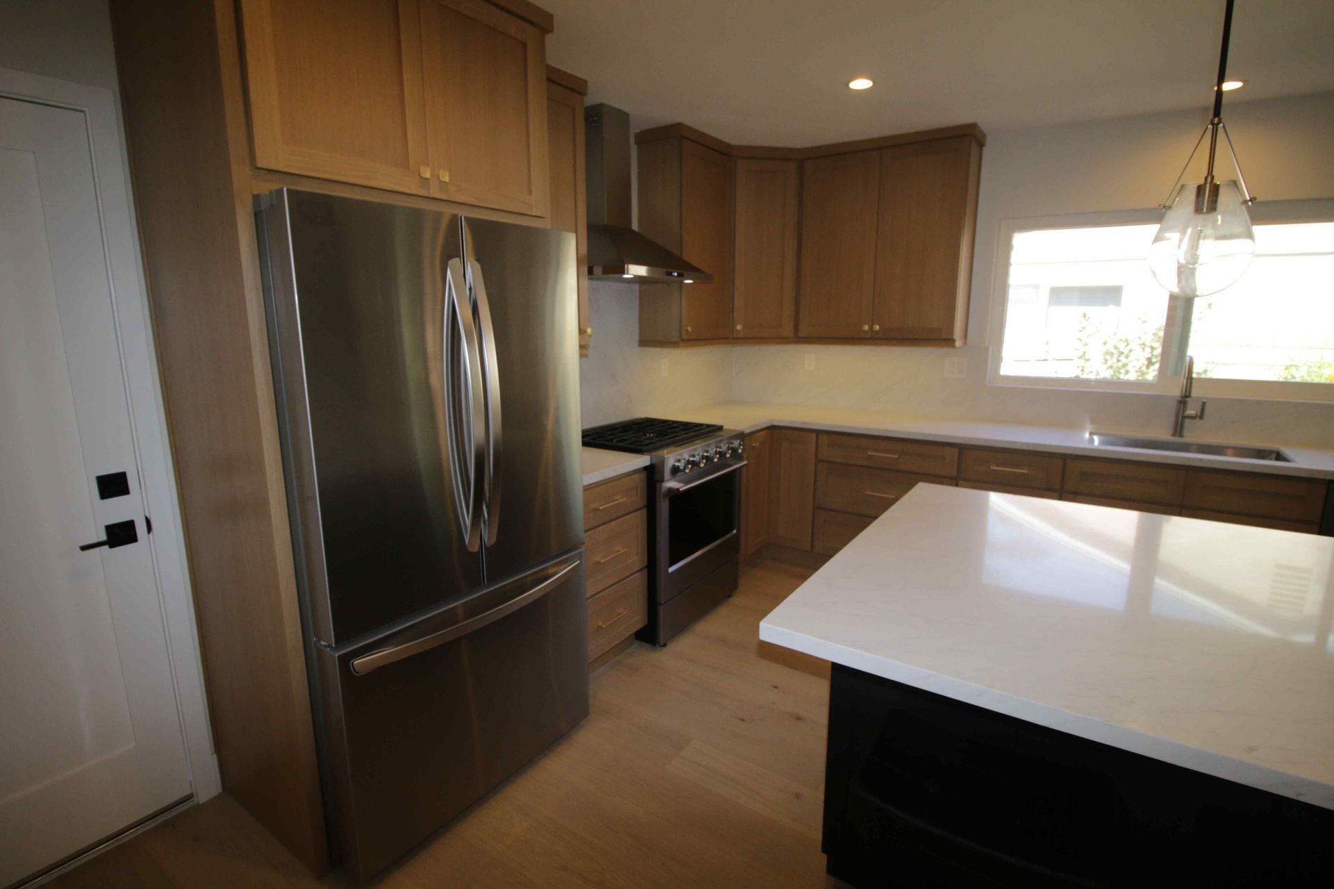 Modern kitchen with stainless steel appliances, wood cabinets, and a white island countertop