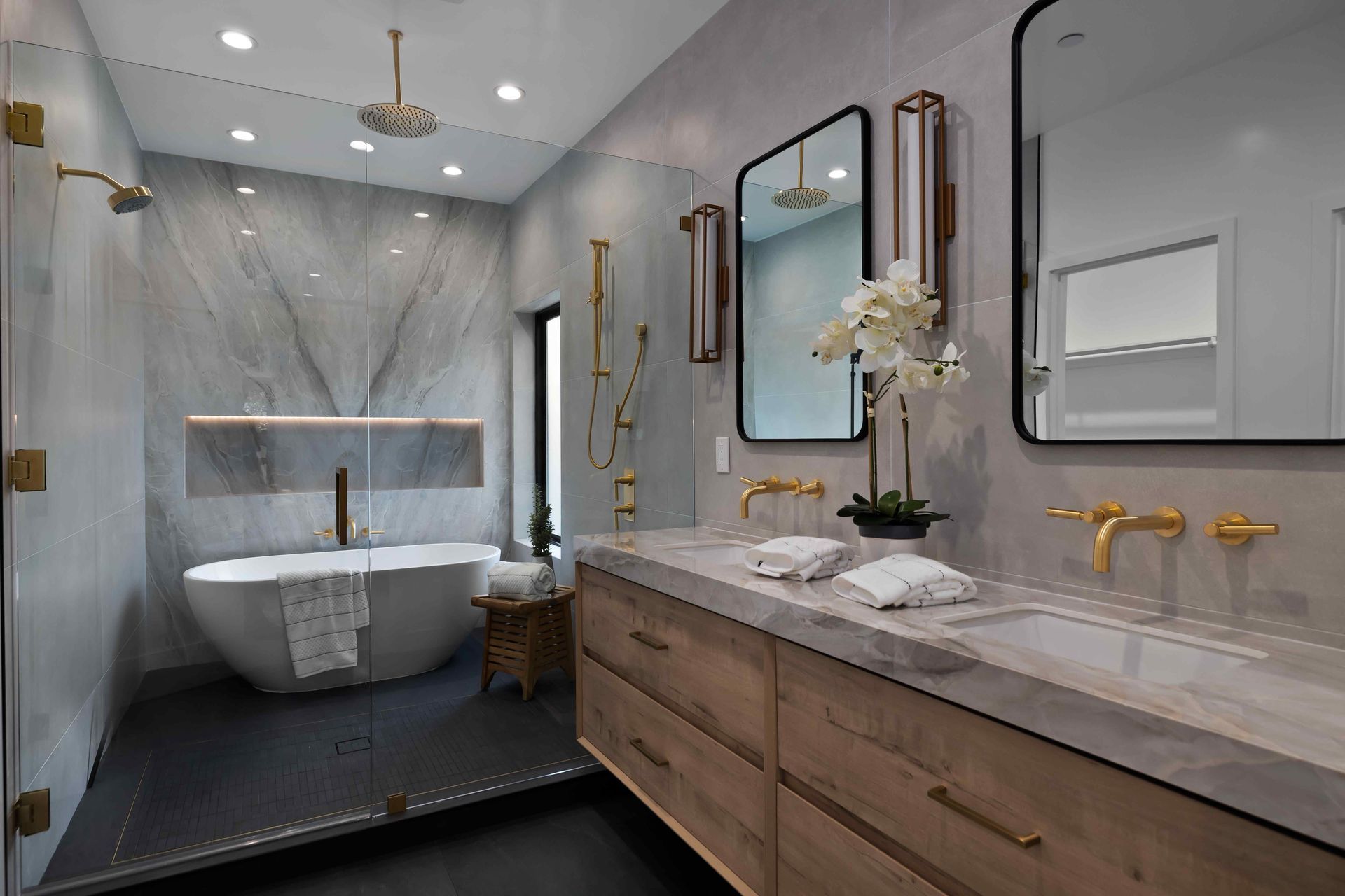 Modern bathroom with a freestanding tub, marble countertops, and gold fixtures.