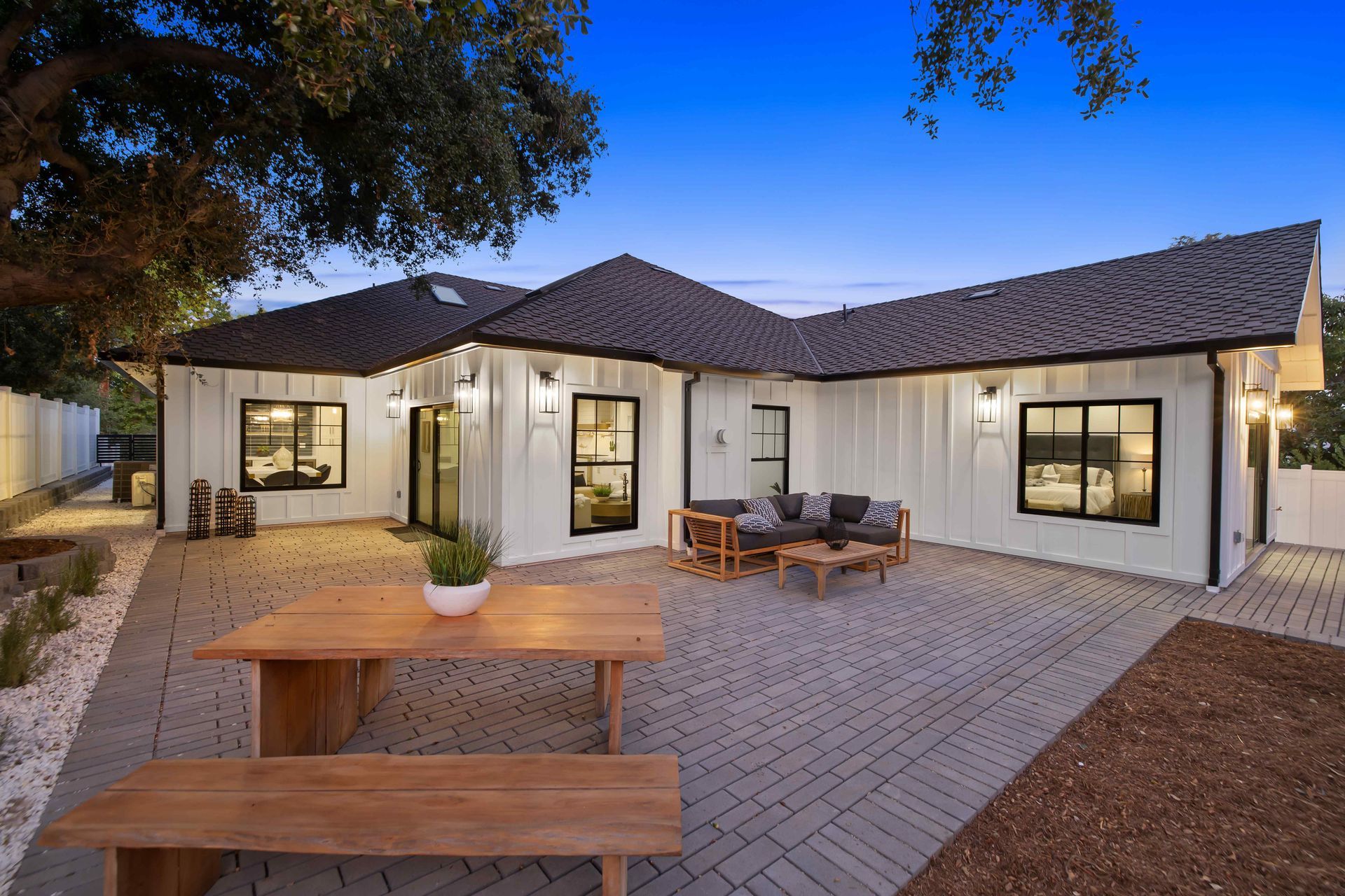 White house with black trim, patio with wooden table and seating.