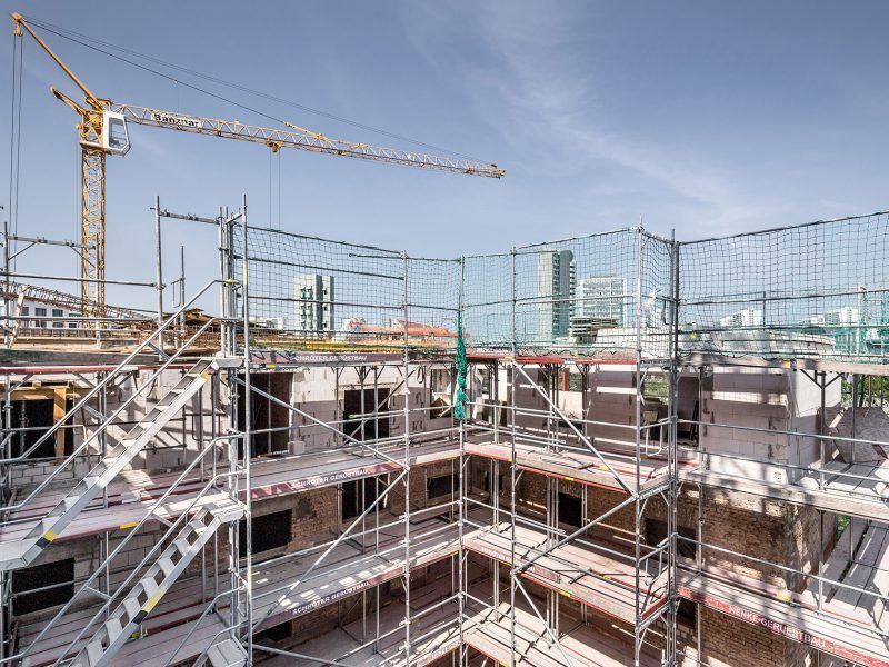 Eine Baustelle mit Gerüst und einem Kran im Hintergrund.