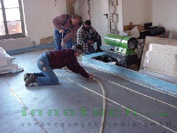 Eine Gruppe von Männern arbeitet in einem Raum an einem Fußboden.