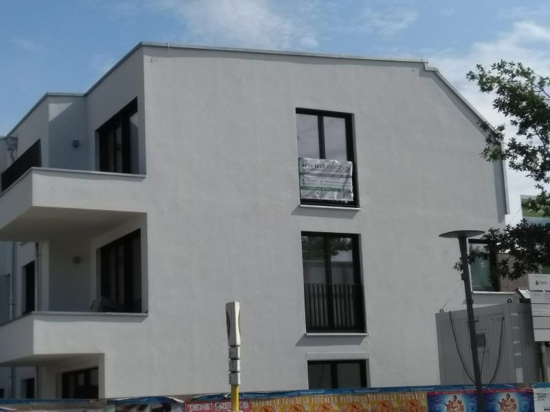 Ein großes weißes Gebäude mit schwarzen Fenstern und einem Balkon