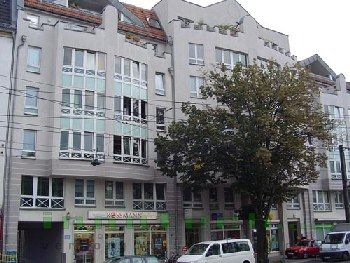 Ein weißer Lieferwagen parkt vor einem großen Gebäude.