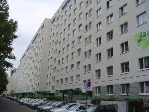 Vor einem großen Gebäude parkt eine Reihe Autos.