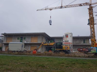 Ein großes Gebäude wird gebaut, im Hintergrund ist ein Kran zu sehen.