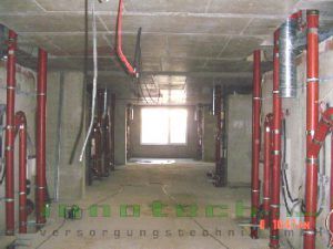 Ein im Bau befindliches Gebäude mit roten Rohren und Kabeln, die von der Decke hängen.