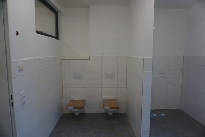 Ein Badezimmer mit zwei Toiletten und einem Fenster.