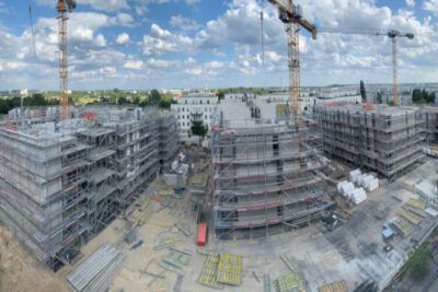 Eine Luftaufnahme eines im Bau befindlichen Gebäudes mit Kränen und Gerüsten.