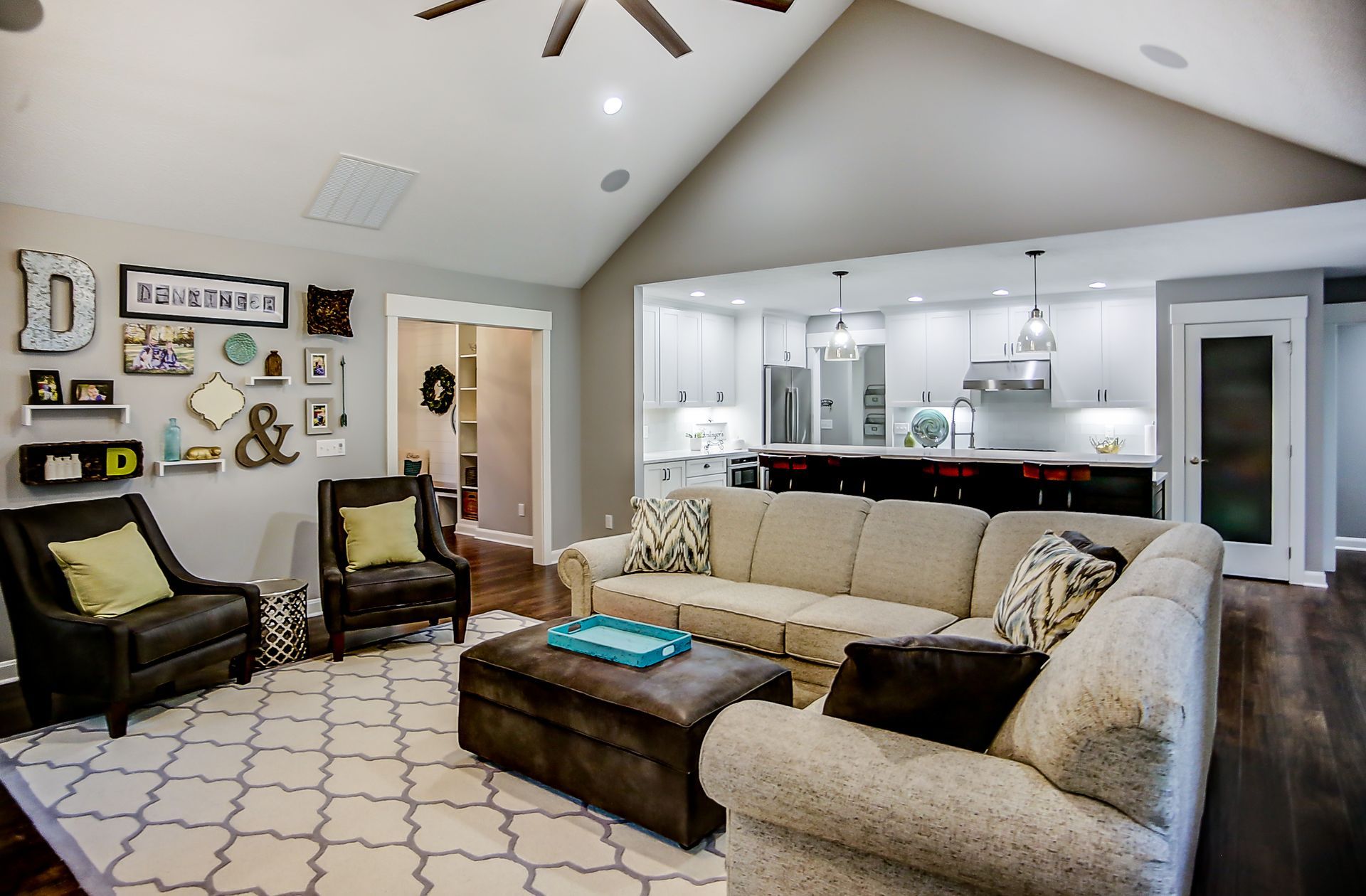 A living room with a couch , chairs , ottoman and ceiling fan.