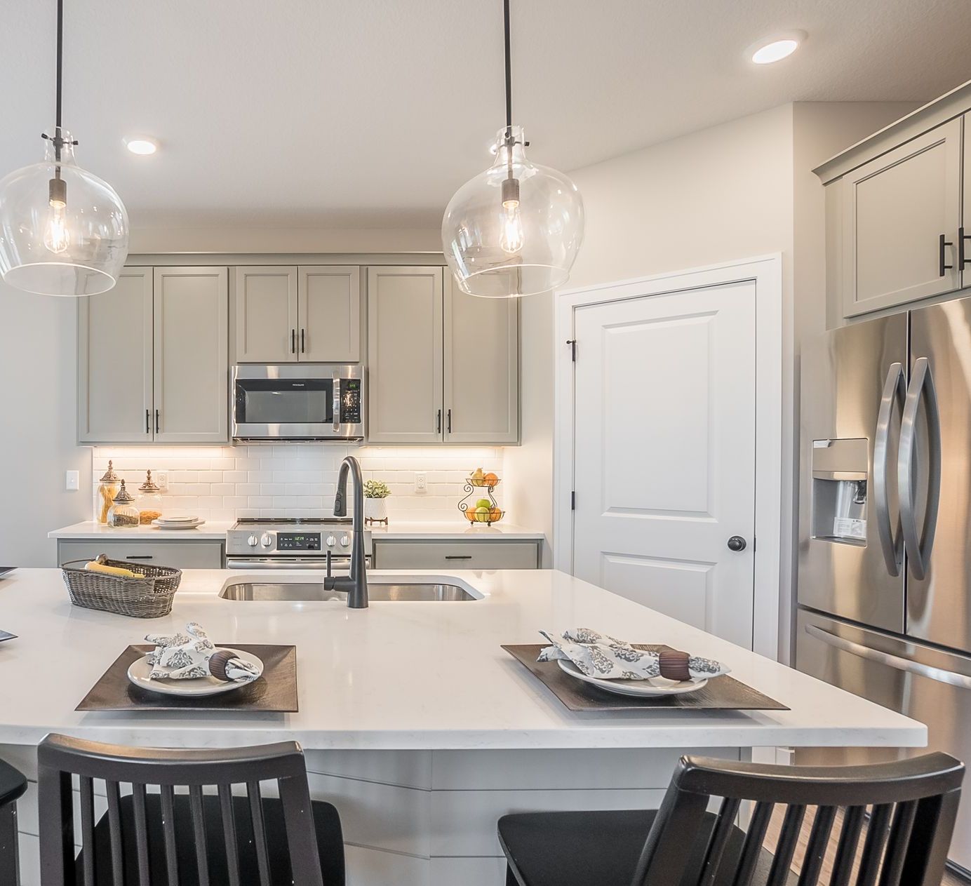 A kitchen with stainless steel appliances and a large island with plates on it.
