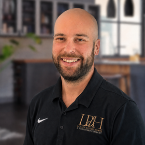 A bald man with a beard is wearing a black shirt and smiling.