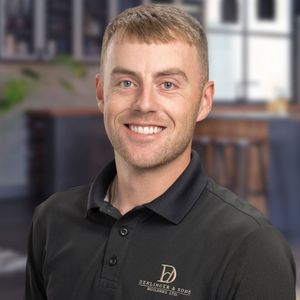A man wearing a black polo shirt is smiling for the camera.