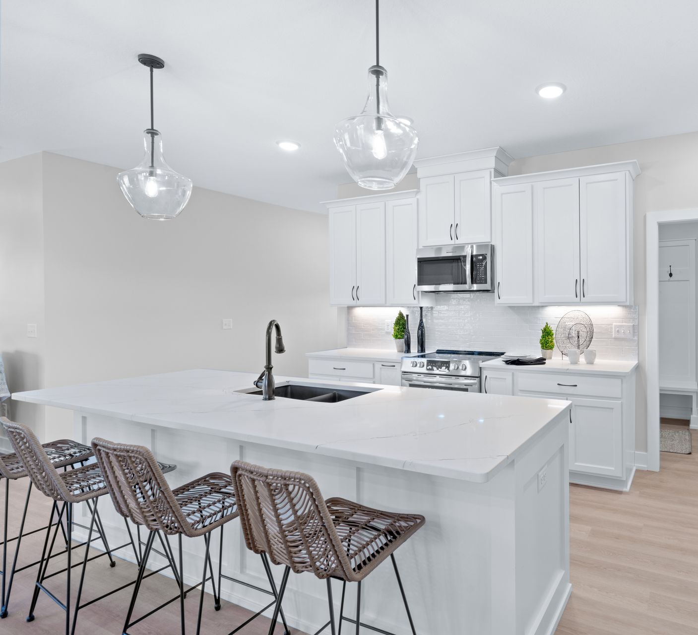 A kitchen with white cabinets and stools and a large island