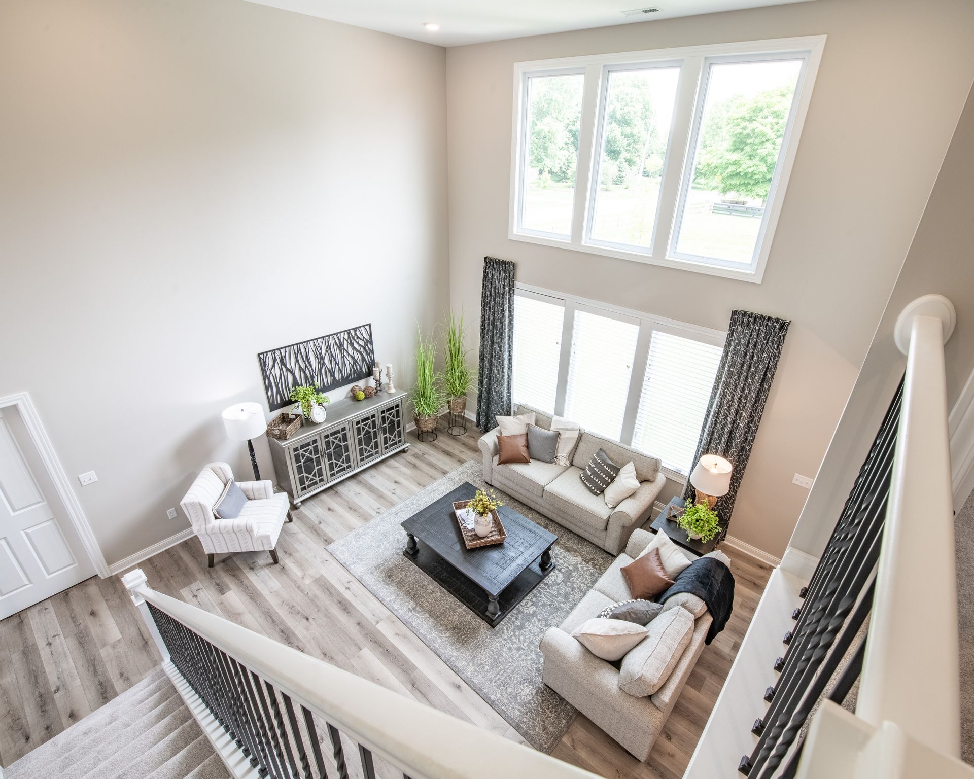 An aerial view of a living room with a couch , chair , coffee table and stairs.
