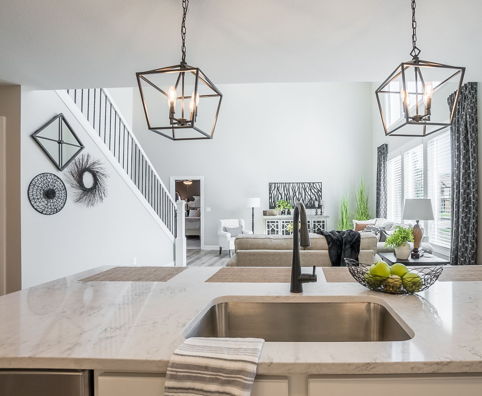 A kitchen with a sink and a living room in the background