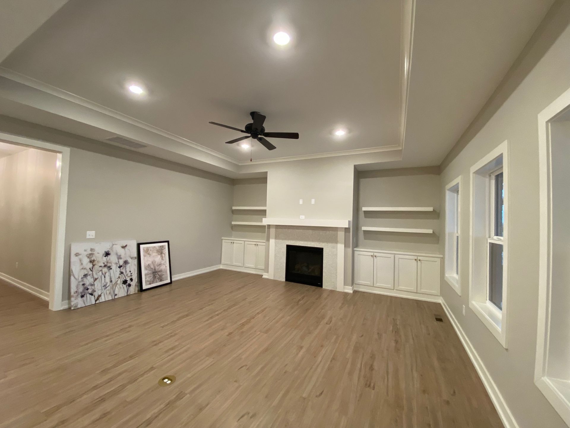 An empty living room with a fireplace and a ceiling fan.