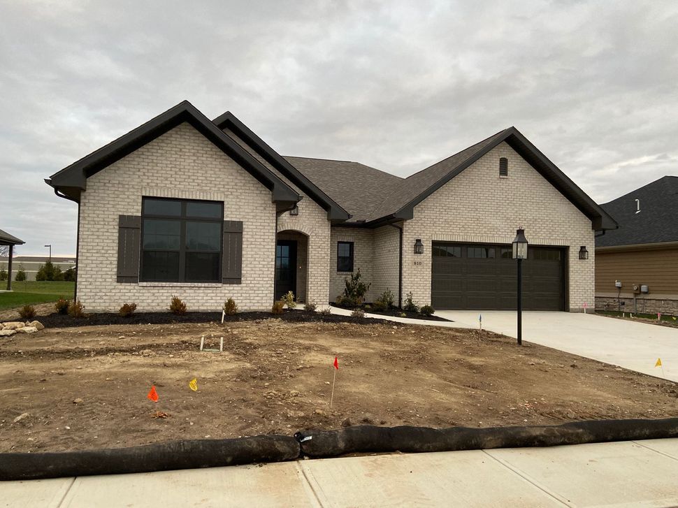 A large brick house with a garage and a lot of dirt in front of it.