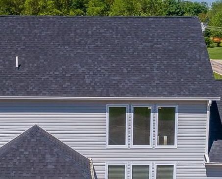 An aerial view of a house with a black roof and white siding.