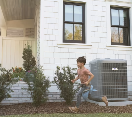 A young boy running in front of a white brick house