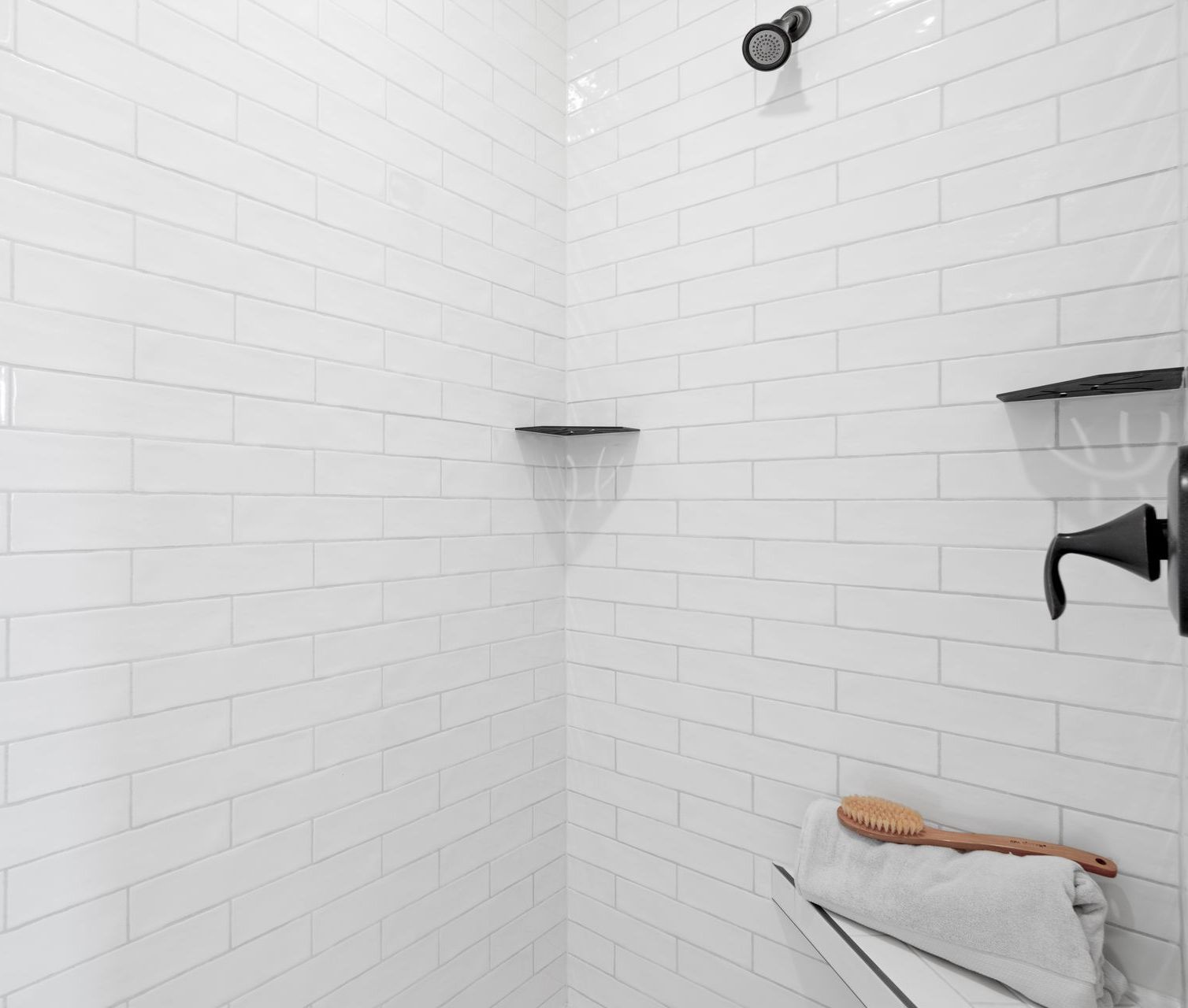 A bathroom with white tiles and a shower head.