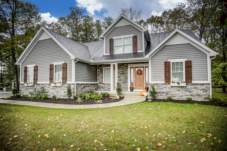 A large gray house with brown shutters and a wreath on the front door.