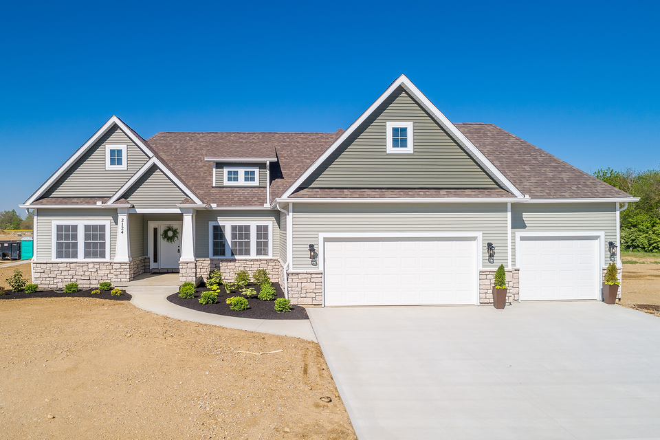 A large house with two garages and a concrete driveway.