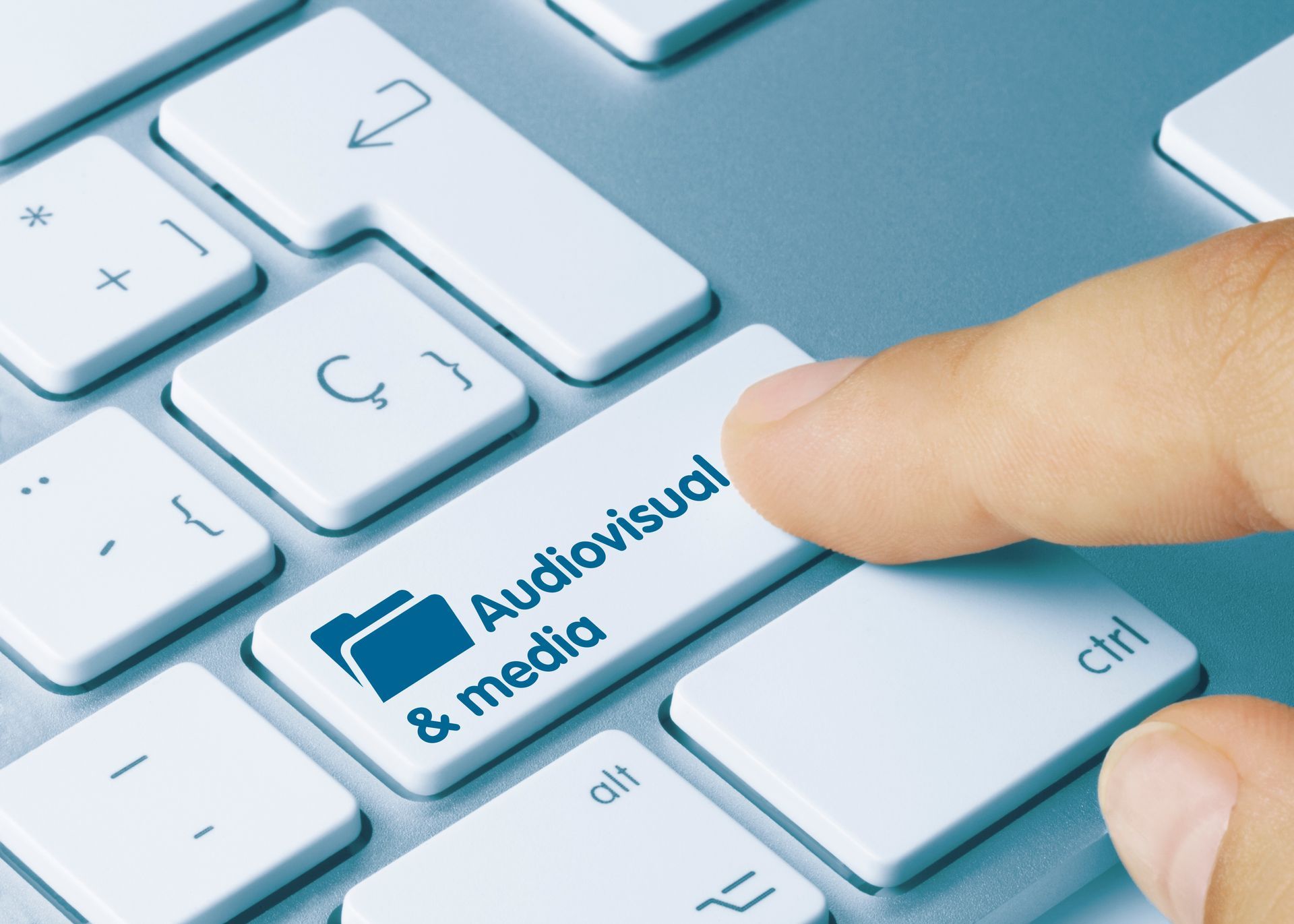 Finger pressing a keyboard key labeled “Audiovisual & media.