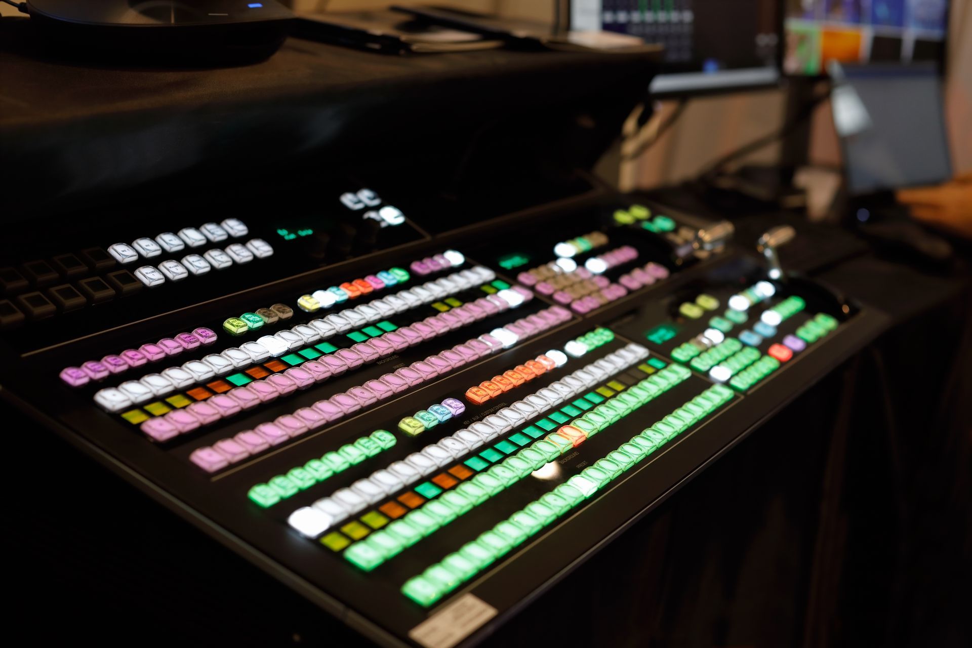 Multicolored illuminated control panel with rows of buttons in a dim studio setting