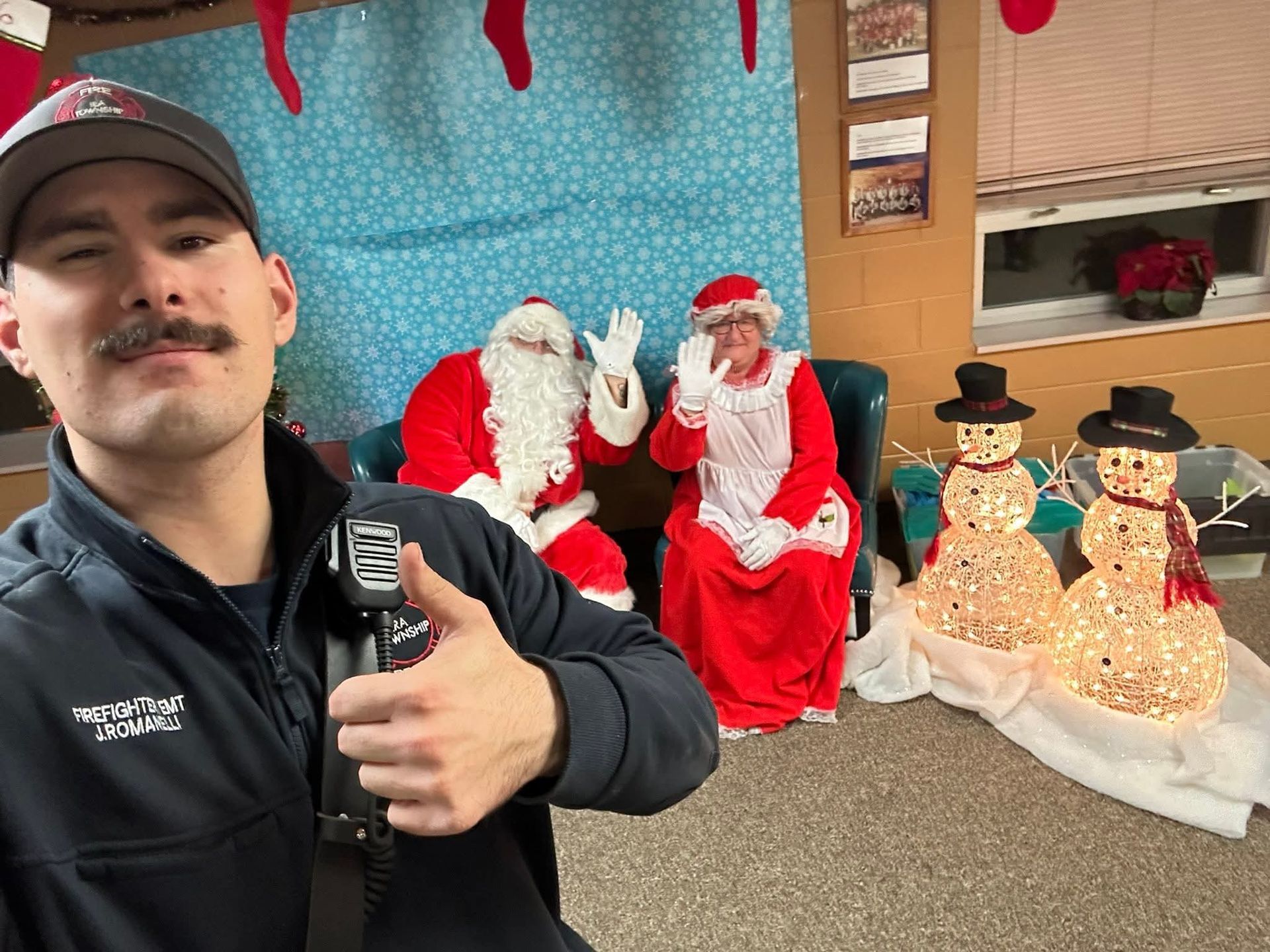 Man taking a selfie beside Santa and holiday snowman decorations in a store display