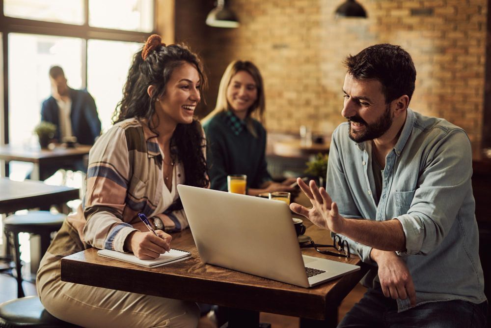 man and woman sitting at a table with a laptop
