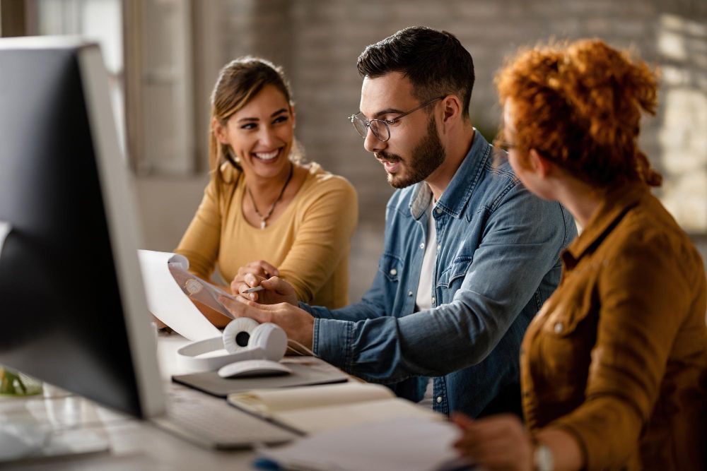 group of people sitting at a table looking at a computer screen