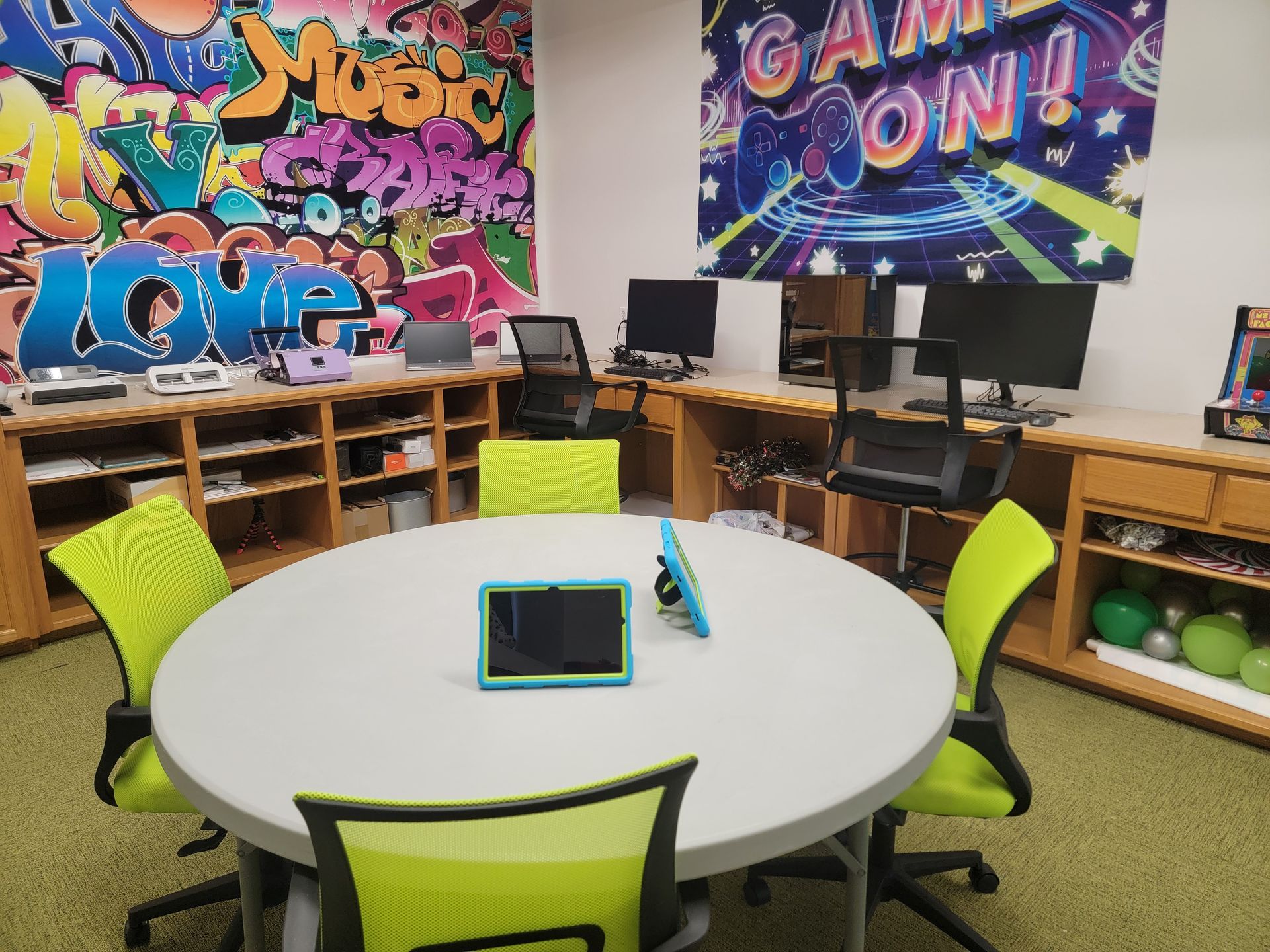 A room with a table and chairs and a graffiti wall that says game on