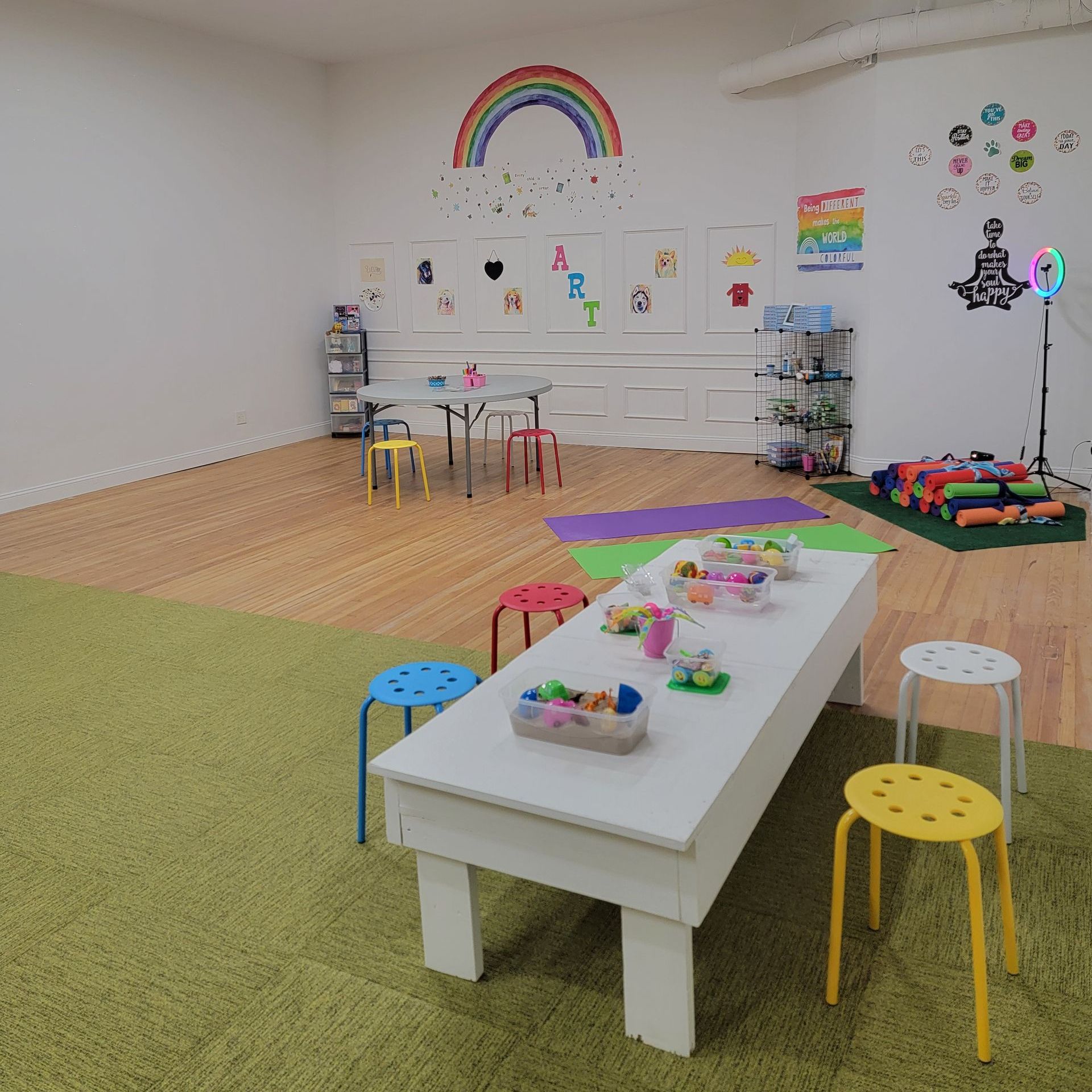 A room with a table and stools and a rainbow on the wall