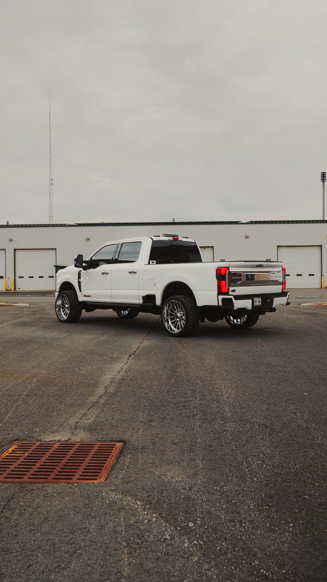 White pickup truck parked on a wet lot near white storage units under an overcast sky