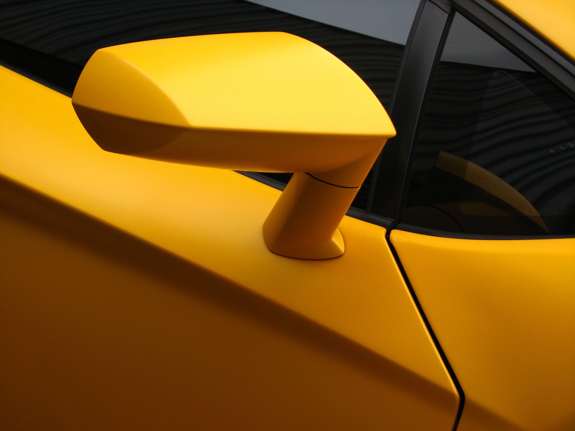 Close-up of a yellow sports car’s side mirror and door panel