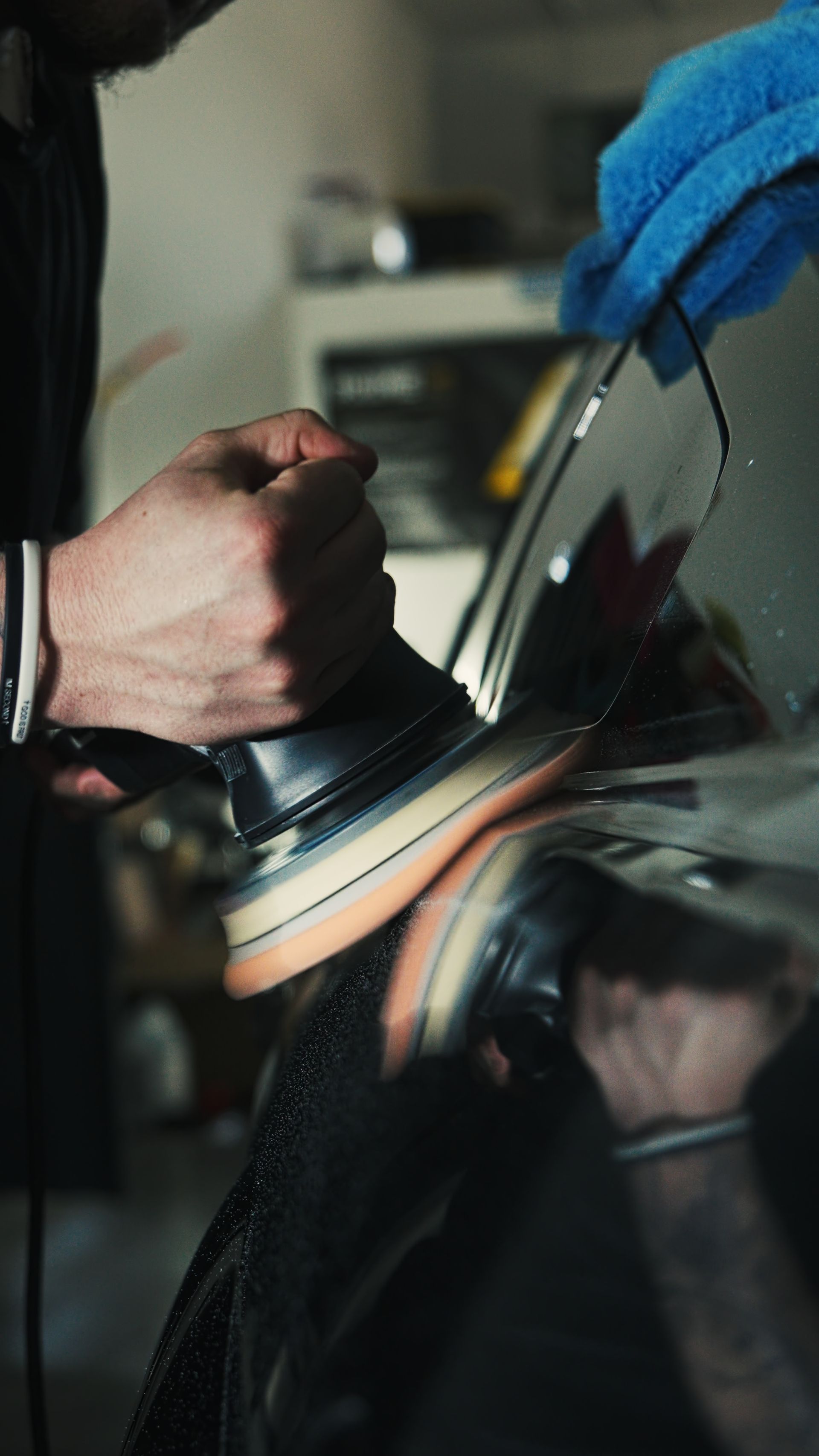 Hands smoothing a piece of leather with a shoe shine brush while wearing blue gloves.