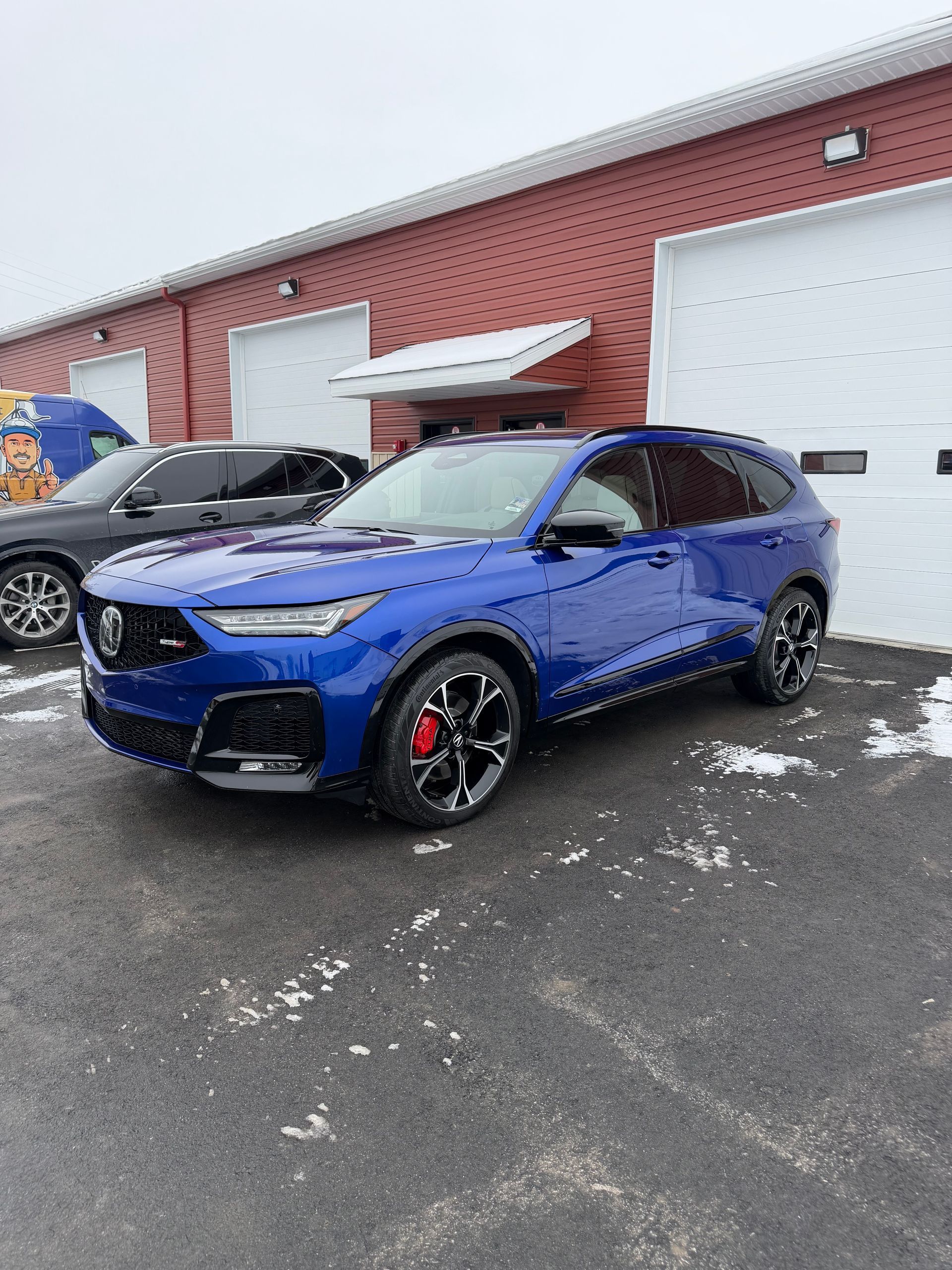 Blue SUV parked outside a red brick building on a snowy lot