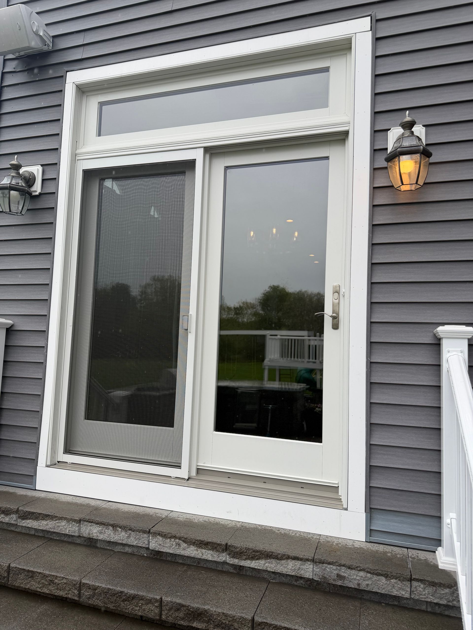 Gray house exterior with a white-framed sliding glass door and narrow transom window above it